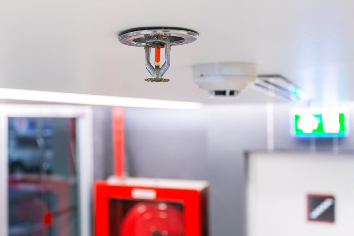 Ceiling mounted wet pipe fire sprinkler head installed near a smoke detector in a commercial building.