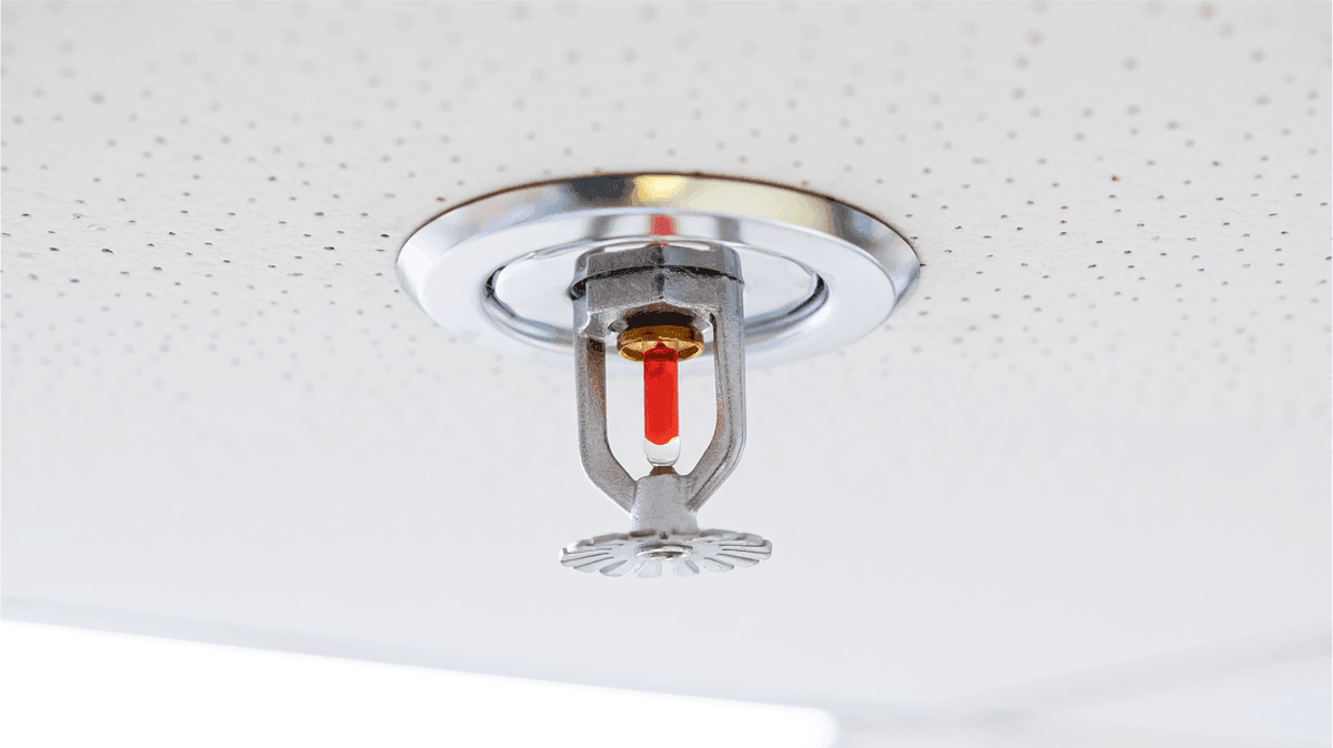 Recessed fire sprinkler installed in a suspended ceiling, demonstrating proper sprinkler placement for coordinated ceiling design.
