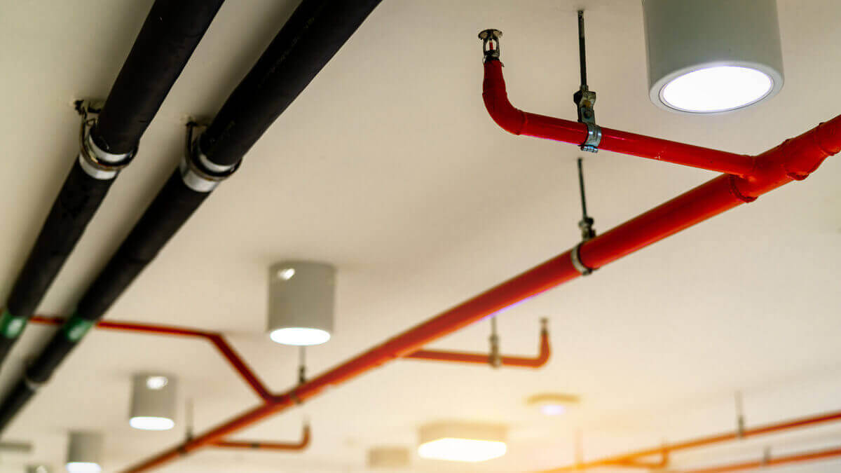 Exposed fire sprinkler piping installed on the ceiling of a commercial building in accordance with fire sprinkler code requirements.
